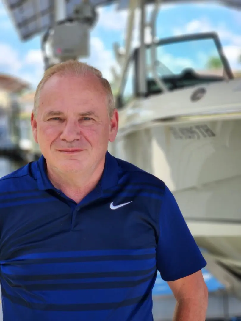 A man in blue shirt standing next to boat.